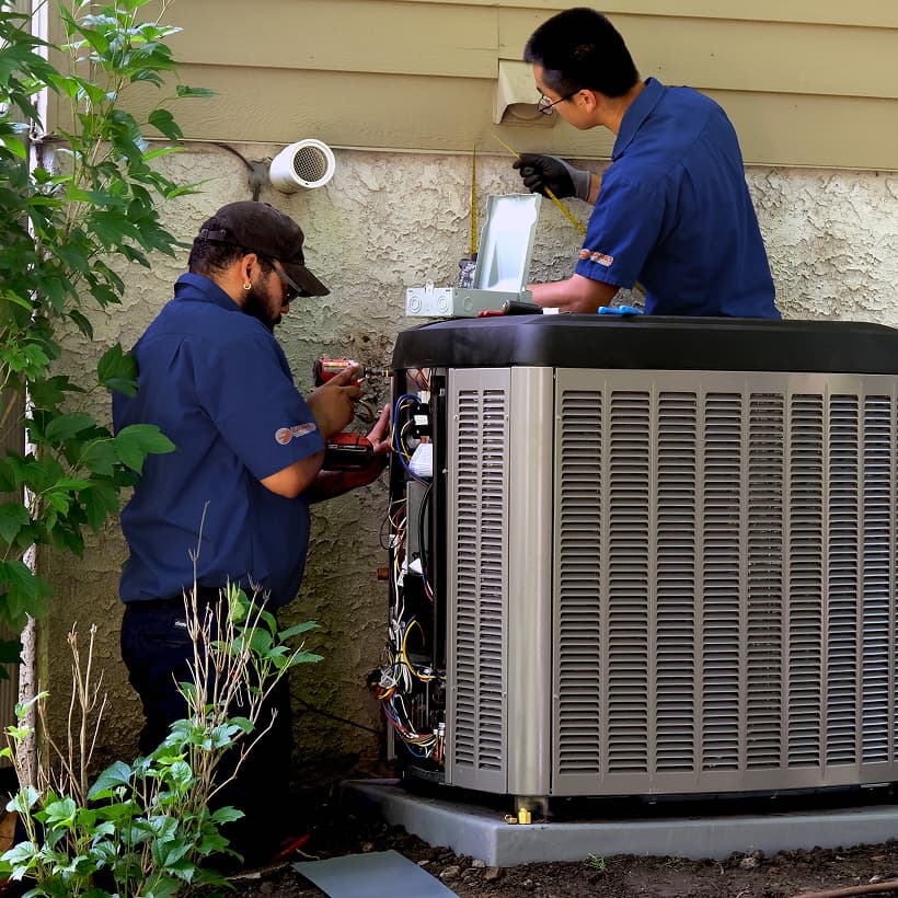 Two Eanes HVAC technicians installing a brand-new residential outdoor air conditioning condenser unit during a home AC replacement service.