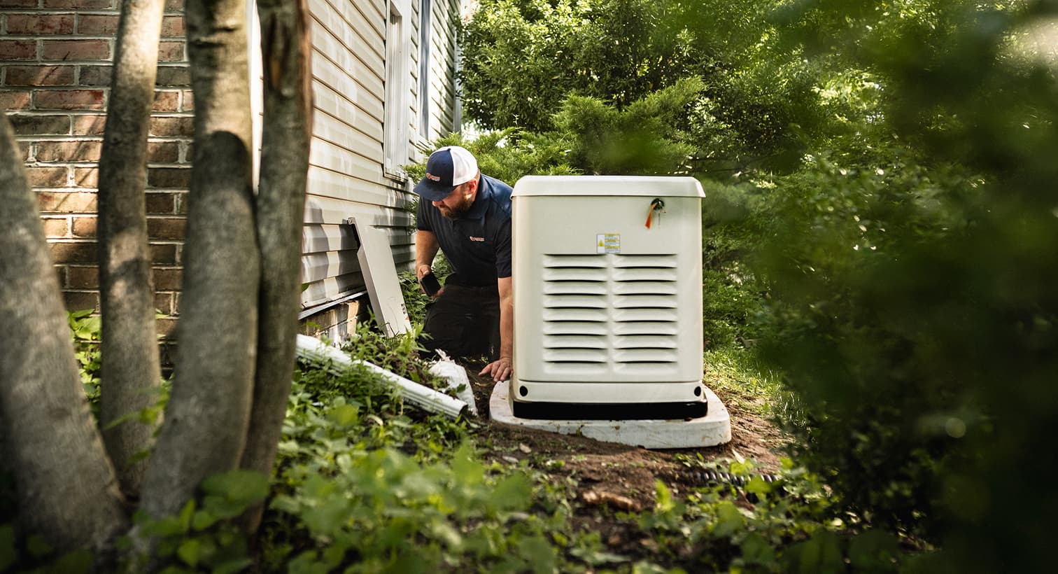 A professional Eanes technician inspects a large, beige whole-home standby generator installed on a concrete pad outside a residential house.
